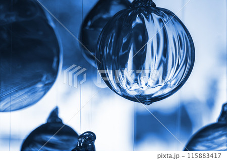 Glass balls hang in front of bright window, close up blue toned photo 115883417