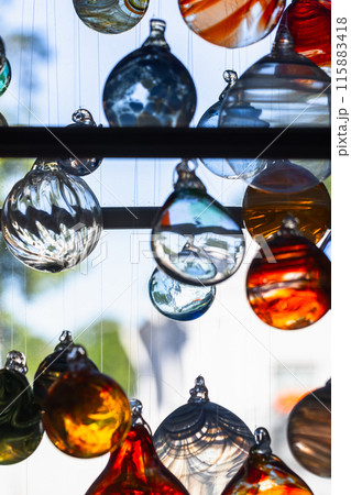 Colorful glass balls hang in front of bright window, vertical photo Colorful glass balls hang in front of bright window, vertical photo 115883418