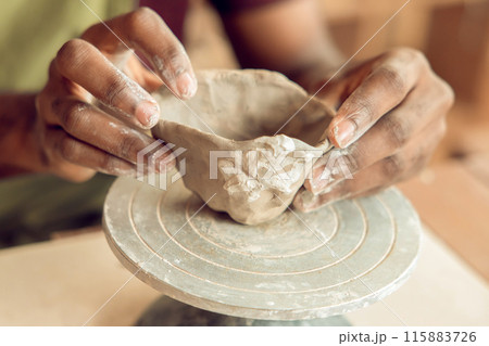 Close up of mans hands molding a shape of clay 115883726