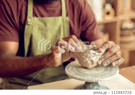 Close up of mans hands molding a shape of clay Close up of mans hands molding a shape of clay 115883728