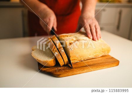 Homemade sourdough bread. Woman hands cuts the bread on cutting board. Handcrafted. Wooden cutting board.  115883995