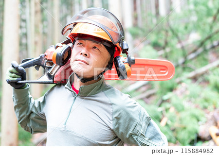 手入れをした森をバックにチェンソーを肩に担いで移動をしようとしているフォレストワーカー 手入れをした森をバックにチェンソーを肩に担いで移動をしようとしているフォレストワーカー 115884982