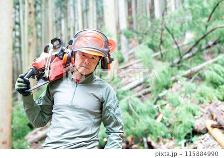 伐採が終了して伐採現場から次の現場に向かってチェンソーを担いで移動しているフォレストワーカー 115884990