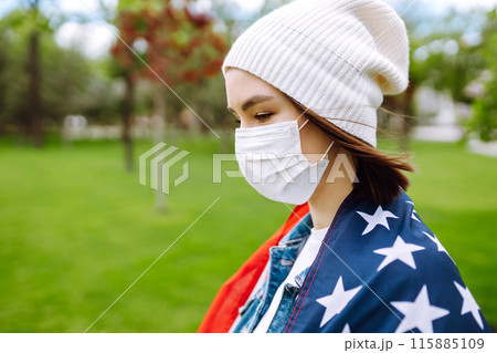 Girl in protective sterile medical mask and with american flag in hand. Quarantine city. Covid -19. 115885109