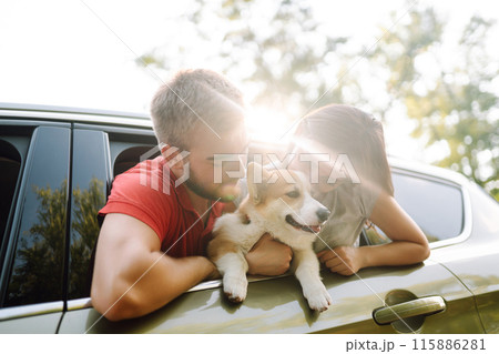 Lovely young couple with dog sits in back seat of car. Concept of active lifestyle, weekend, relax. Lovely young couple with dog sits in back seat of car. Concept of active lifestyle, weekend, relax. 115886281