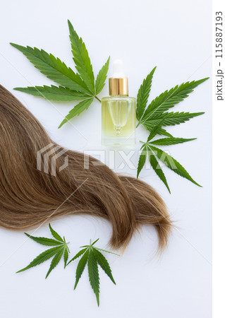 Lock of hair with small bottle of cannabis oil and fresh green cannabis leaves.  115887193