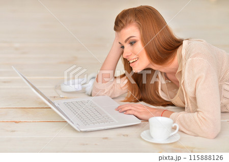 Adult beautiful woman lying on floor with laptop Adult beautiful woman lying on floor with laptop 115888126