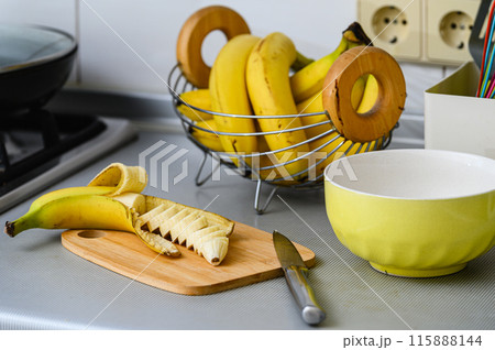 Peeled and sliced banana on a cutting board. 115888144