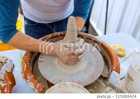Professional potter creating bowl with wet soft clay on potter wheel 115888424
