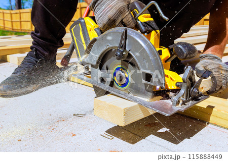 Wood beams are cut using an electrically powered circular saw Wood beams are cut using an electrically powered circular saw 115888449