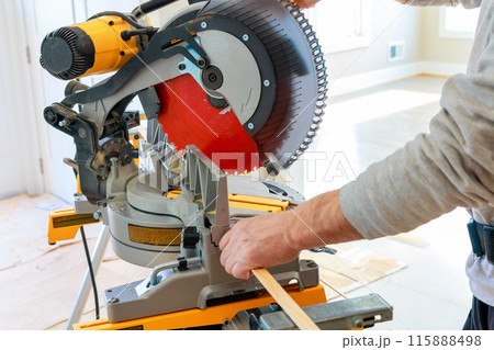 Contractor using circular saw cuts wooden moldings before installing them 115888498