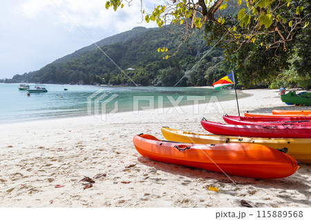 Red plastic kayaks lay on the coast. Summer beach landscape Red plastic kayaks lay on the coast. Summer beach landscape 115889568