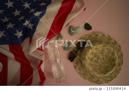 straw hat, sunglasses, bottle of water, sunscreen spray, american flag on colored background 115890414
