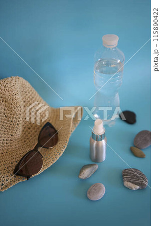 straw hat, sunglasses, bottle of water, sun spray, pebbles on a colored background straw hat, sunglasses, bottle of water, sun spray, pebbles on a colored background 115890422