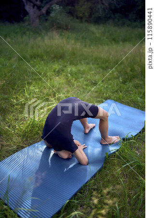 little 5-year-old girl in a black minimalist overall does gymnastics in the garden, outdoors little 5-year-old girl in a black minimalist overall does gymnastics in the garden, outdoors 115890441