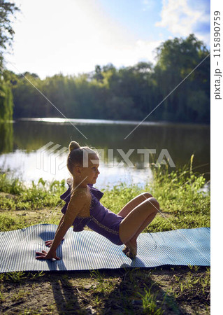a llittle 5-year-old girl in a black minimalist jumpsuit does gymnastics by the river, outdoors a llittle 5-year-old girl in a black minimalist jumpsuit does gymnastics by the river, outdoors 115890759