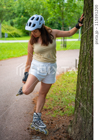 Roller skater woman warming up in park before rollerblading on inline skates. Outdoor activities. Summer roller skating. Roller skater woman warming up in park before rollerblading on inline skates. Outdoor activities. Summer roller skating. 115891200