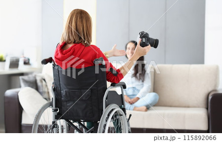 Woman in wheelchair with camera conducts home photo session 115892066