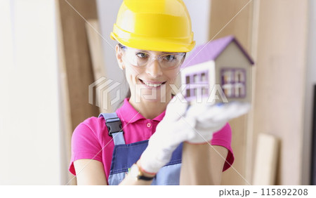 Smiling woman builder holding house in her hands Smiling woman builder holding house in her hands 115892208