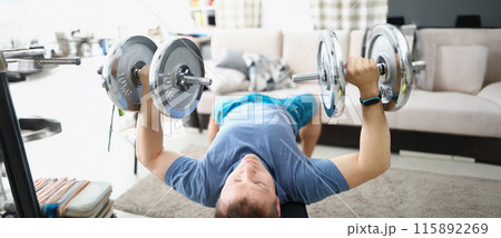 Young man doing exercises with heavy dumbbells for muscles of biceps 115892269