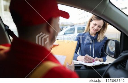 Woman signing documents and receiving yellow postal envelope 115892542