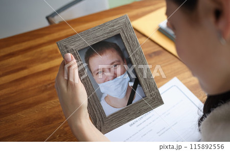 Woman crying over portrait of deceased young man closeup Woman crying over portrait of deceased young man closeup 115892556