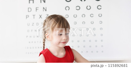 Little girl sitting near table for eye examination 115892681