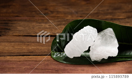 A basket filled with white alum crystals sits on a vibrant green shrub background. A basket filled with white alum crystals sits on a vibrant green shrub background. 115893789