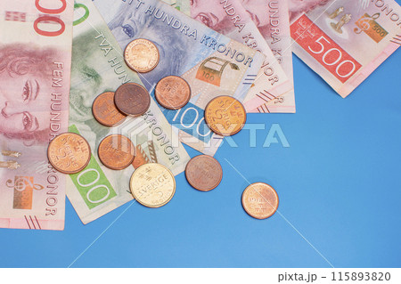 Swedish krona banknotes of different denominations and coins on a blue background Swedish krona banknotes of different denominations and coins on a blue background 115893820