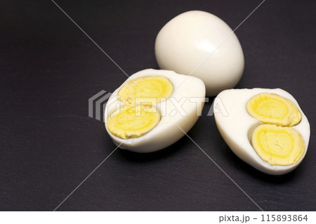egg with two yolks on a black background. 115893864