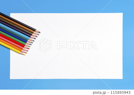 colored pencils and a white empty sheet of paper on a blue background colored pencils and a white empty sheet of paper on a blue background 115893943