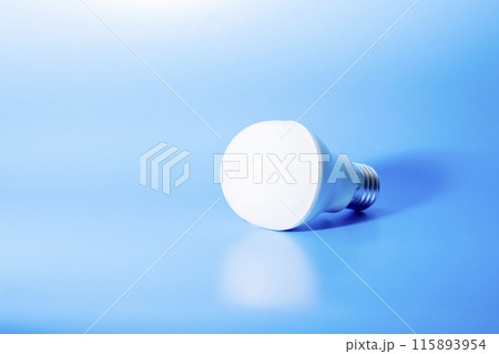 a glowing led light bulb casts a shadow on a blue background. conceptual photography 115893954