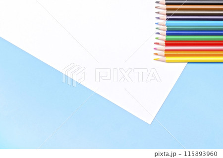 colored pencils and a white empty sheet of paper on a blue background colored pencils and a white empty sheet of paper on a blue background 115893960