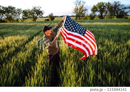 Man hold waving american USA flag. Patriot raise national american flag. Independence Day, 4th July. 115894141