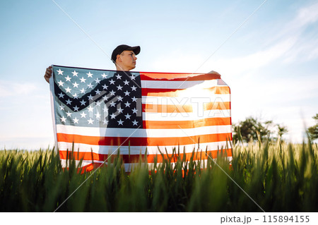 Man hold waving american USA flag. Patriot raise national american flag. Independence Day, 4th July. Man hold waving american USA flag. Patriot raise national american flag. Independence Day, 4th July. 115894155