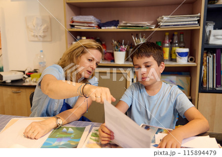 Teacher providing guidance to a student during an art class, reviewing and discussing drawings, fostering creativity and learning in the workshop. Teacher providing guidance to a student during an art class, reviewing and discussing drawings, fostering creativity and learning in the workshop. 115894479