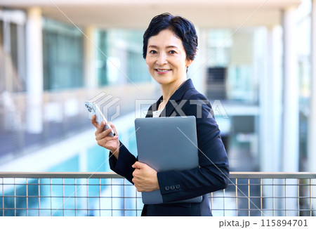 オフィスでスマホを持ったミドルビジネスウーマン オフィスでスマホを持ったミドルビジネスウーマン 115894701