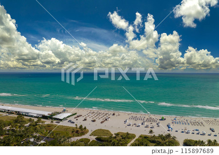 Tourism infrastructure in southern USA. South Beach sandy surface with tourists relaxing on hot Florida sun. Miami Beach city with high luxury hotels and condos 115897689