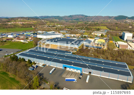 Aerial view of solar power plant with blue photovoltaic panels mounted on industrial building roof for producing green ecological electricity. Production of sustainable energy concept 115897693