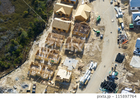 Wooden houses under construction in new developing suburban area. Development of residential housing in American suburbs. Real estate market in the USA Wooden houses under construction in new developing suburban area. Development of residential housing in American suburbs. Real estate market in the USA 115897764