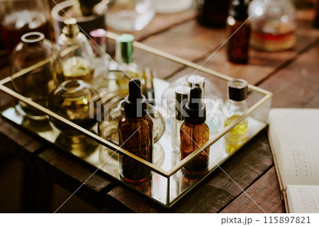 Medium close up of brown glass bottle with pipette full of essential oils and multicolored crystal flask with essences in glass box with golden frames 115897821