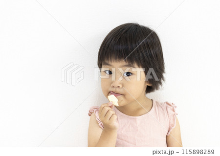 ポテトチップスを食べて舌を出す女の子（3歳、日本人、ショートヘア） 115898289