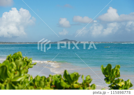 A blurry beach with an island, water, clouds, vegetation, azure sky 115898778