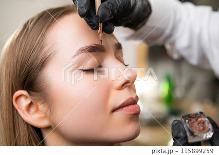 Woman defines ideal shape as preliminary step to lamination process. Professional ensures flawless shape for young lady during procedure Woman defines ideal shape as preliminary step to lamination process. Professional ensures flawless shape for young lady during procedure 115899259