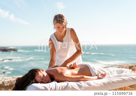 Masseur massaging female body outdoor 115899716