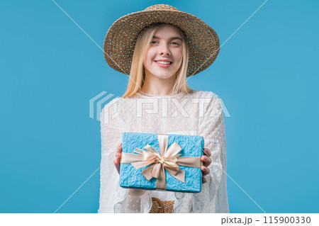 Happy blonde woman gift box on blue background. Young girl smiling, gives you 115900330