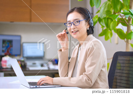 オフィスで仕事をするヘッドセットを付けたミドル女性 115901818