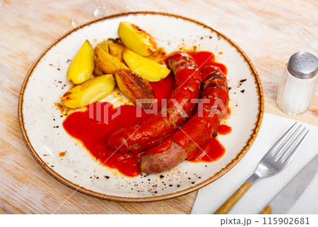 Sausages with potato slices in tomato sauce 115902681