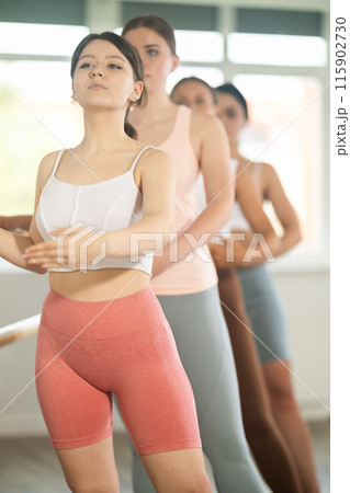 Young girl practicing first arm position holding by ballet barre Young girl practicing first arm position holding by ballet barre 115902730