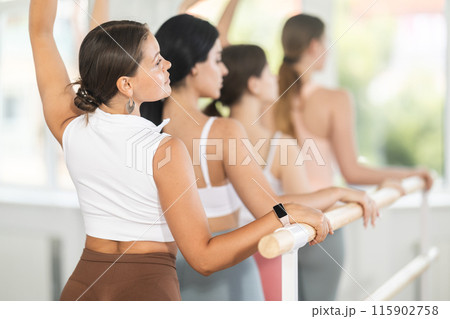 Young girl practicing third arm position holding by ballet barre Young girl practicing third arm position holding by ballet barre 115902758